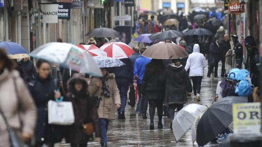 Gente protegiéndose de la lluvia en una calle en A Coruña.