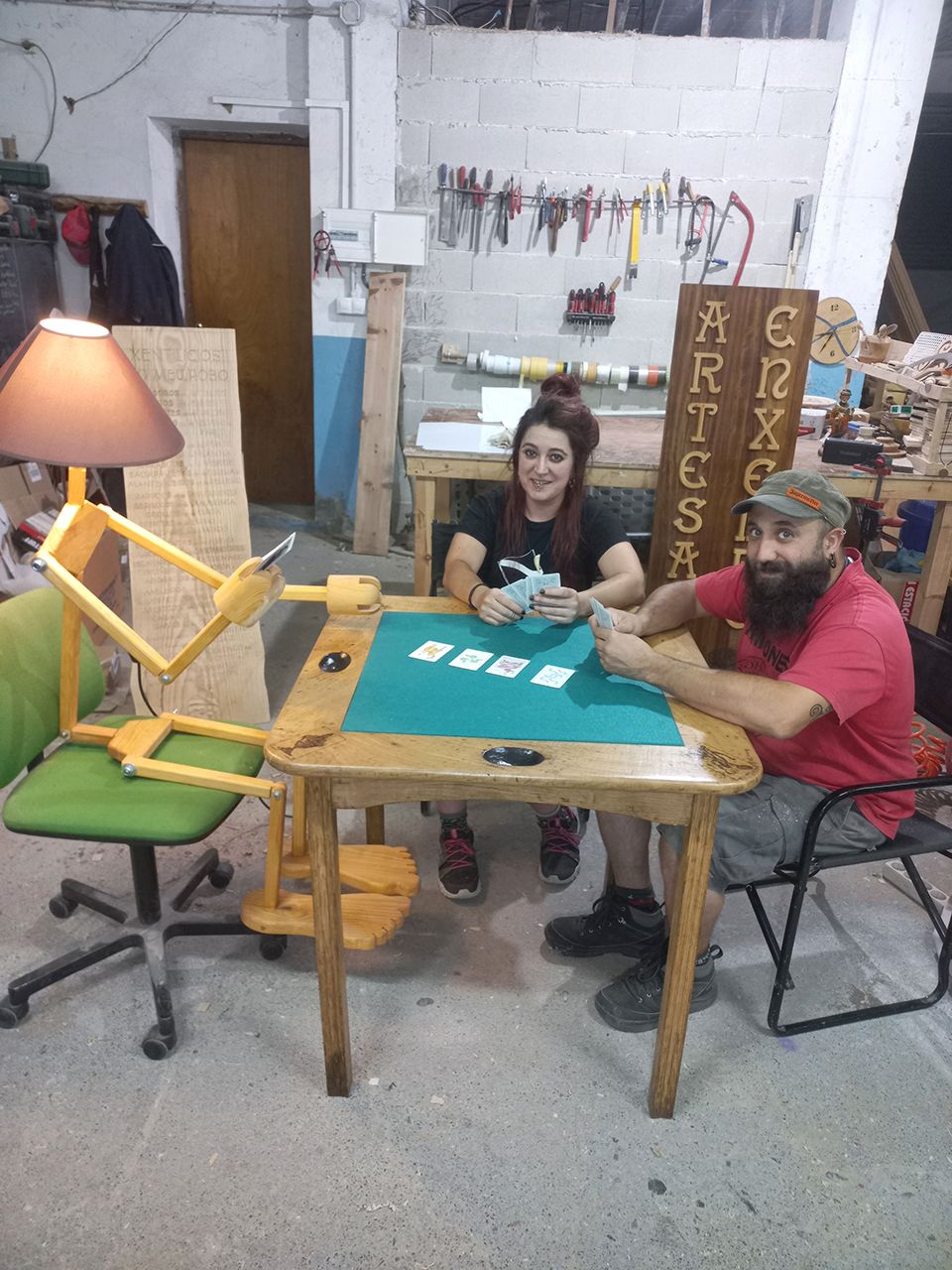 Sarah y Lalo en su taller con una de sus ingeniosas lámparas y otros objetos que elaboran con madera usada: desde cabeceros de cama a estanterías o muebles.