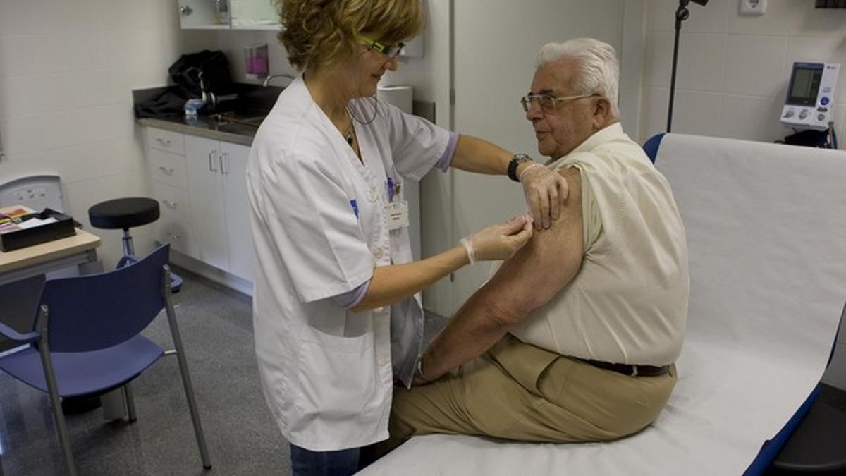 Una enfermera suministra la vacuna contra la gripe a un usuario, en un CAP de Les Corts.