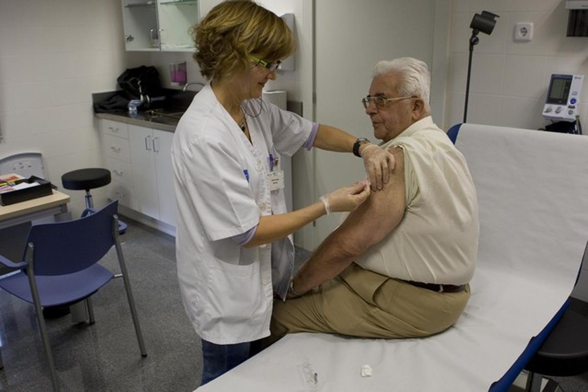 Una enfermera suministra la vacuna contra la gripe a un usuario, en un CAP de Les Corts.