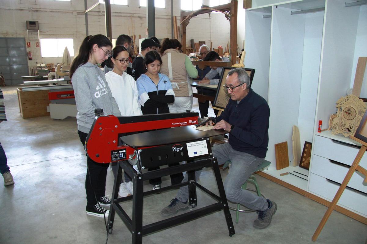 El maestro artesano Joaquín Feria hace una demostración a varias estudiantes en su taller Carpinfe.