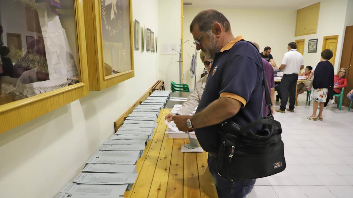 Un elector recoge papeletas y sobres de la formación a la que quiere votar, en una mesa electoral en mayo de 2019.