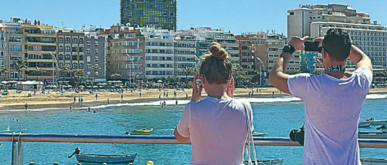 Una pareja de turistas fotografía la capital grancanaria desde Las Canteras.