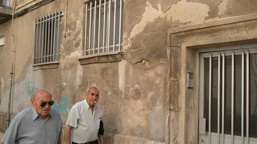 La fachada de la calle Pintor Cabrera, ante la que pasan dos transeúntes, evidencia el deterioro del grupo de casas de Sant Jordi.