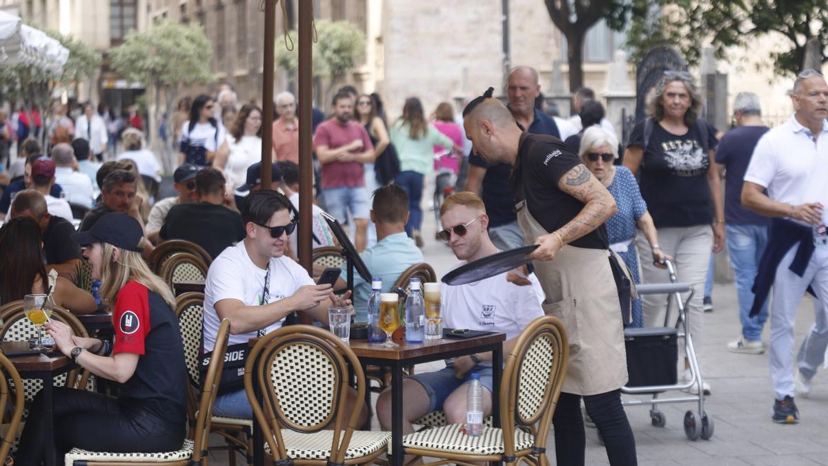 Un treballador atén una taula en una cafeteria del centre de València.