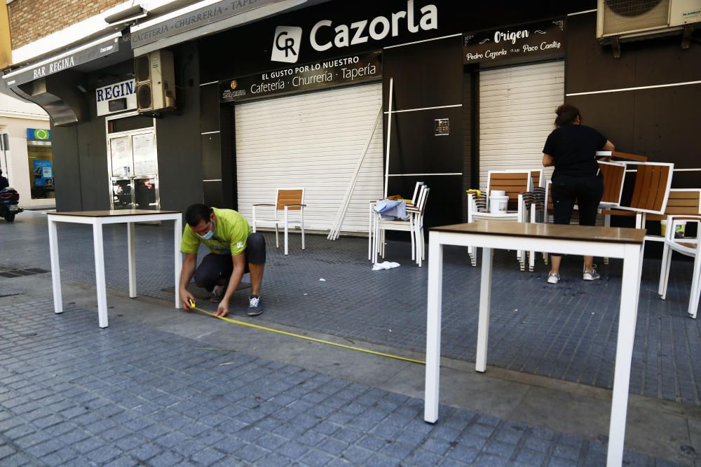 Imágenes de una lluviosa mañana de jueves en el centro de Málaga, donde al paisaje ya habitual de pocas personas y la mayoría de ellas con guantes y mascarillas se le han añadido los preparativos de bares, cafeterías y terrazas que se preparan para el inminente cambio de fase de la desescalada de la ciudad.