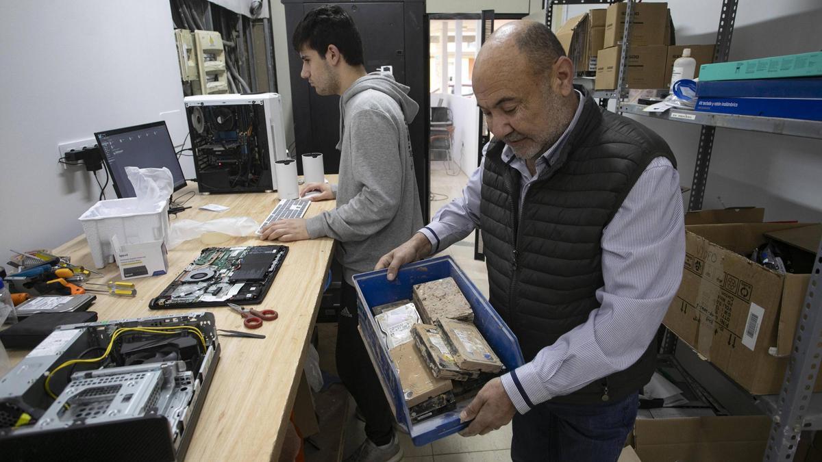García muestra discos duros afectados por la dana de octubre, en su tienda.