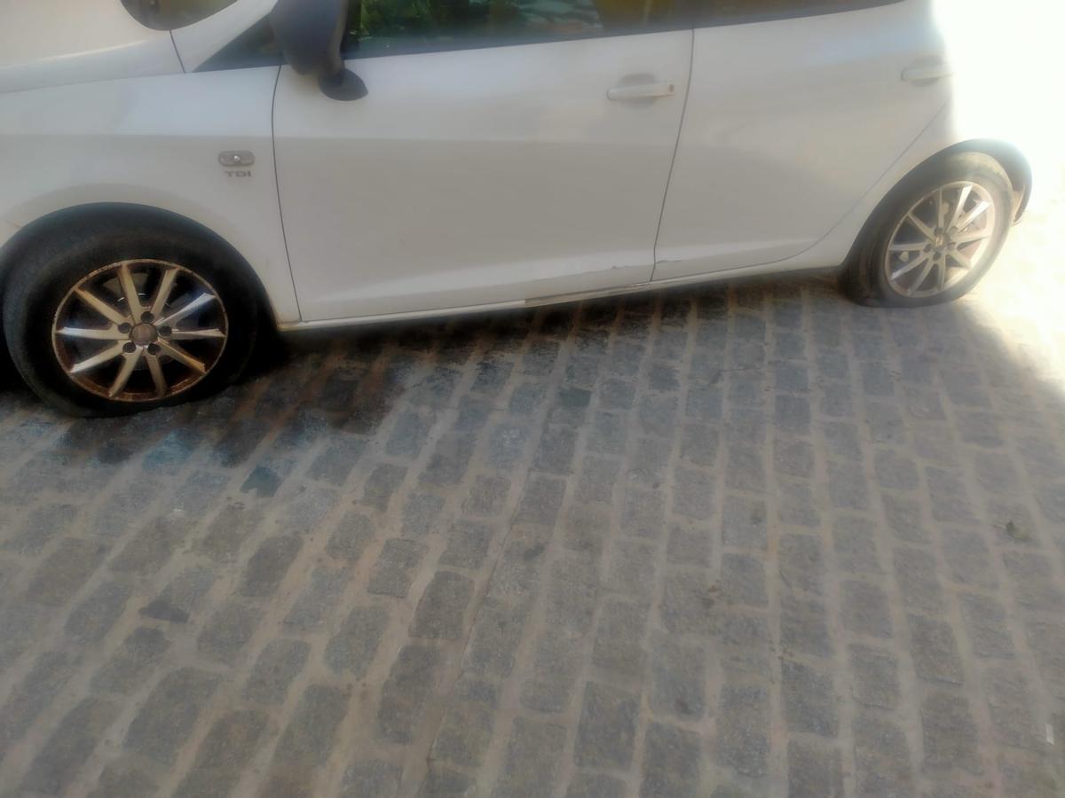 Coche con dos ruedas pinchadas.