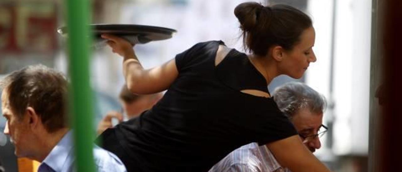 Una joven camarera atiende a los clientes en una terraza de Valencia.