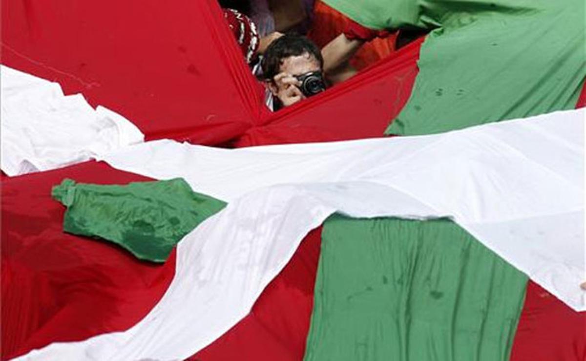Un jove fa una fotografia, a través d’un forat, d’una ’ikurriña’ que diversos joves van aconseguir passar malgrat els controls policials.
