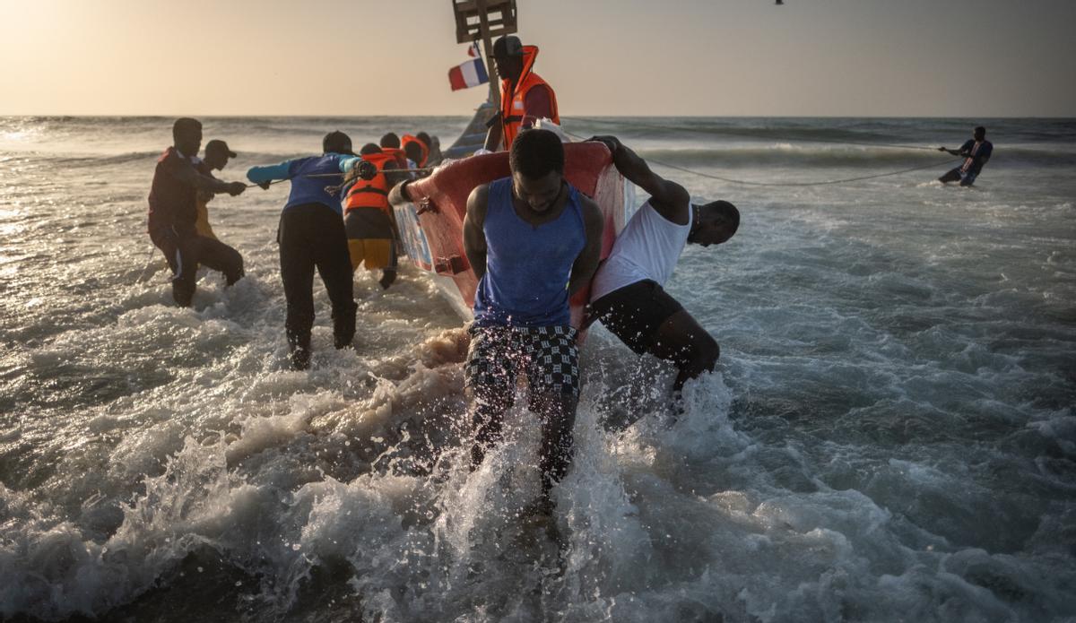 Un grupo de pescadores entran en el mar con un cayuco en el barrio de Guet N’Dar, en Saint Louis, Senegal
