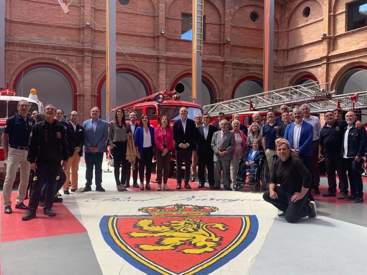 Representantes políticos y del Real Zaragoza junto a los bomberos y su banderín de grandes dimensiones