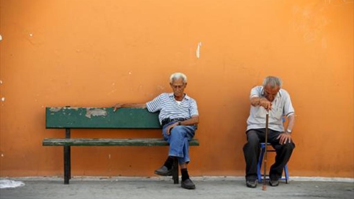 Dos hombres están sentados en la calle con el rostro abatido en el pueblo griego de Meyisti, ayer.