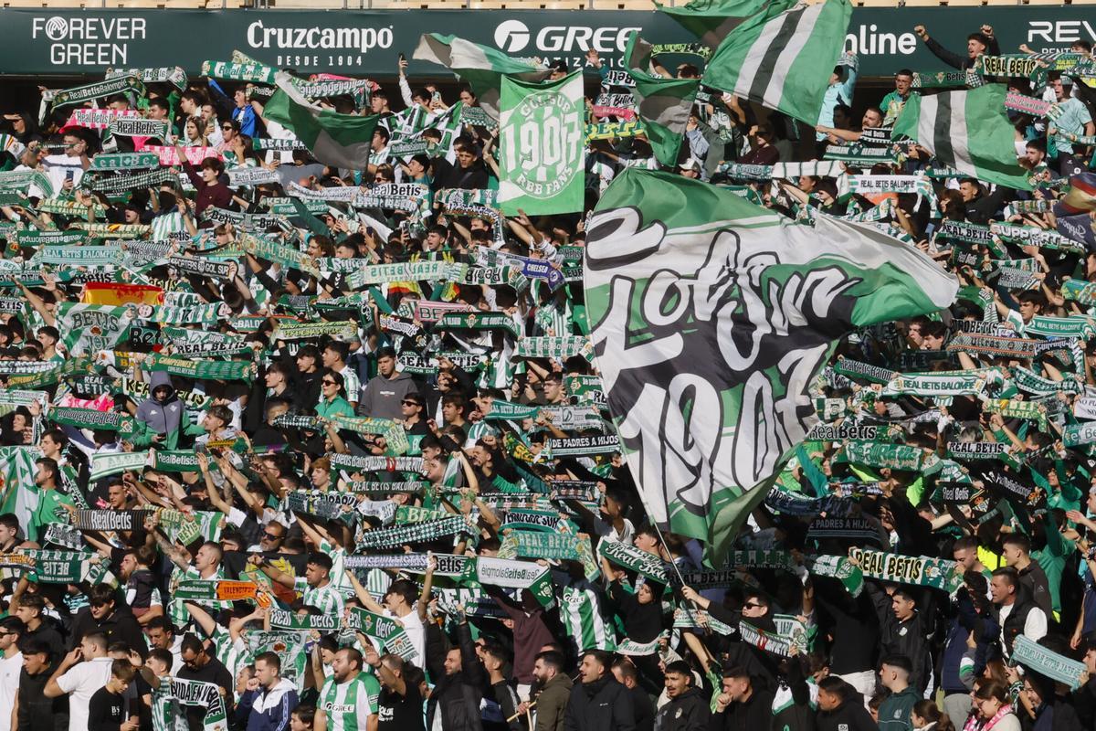 Aficionados béticos animan a su equipo durante el entrenamiento celebrado este sábado en el estadio de La Cartuja de cara al partido que disputarán mañana frente al Sevilla.