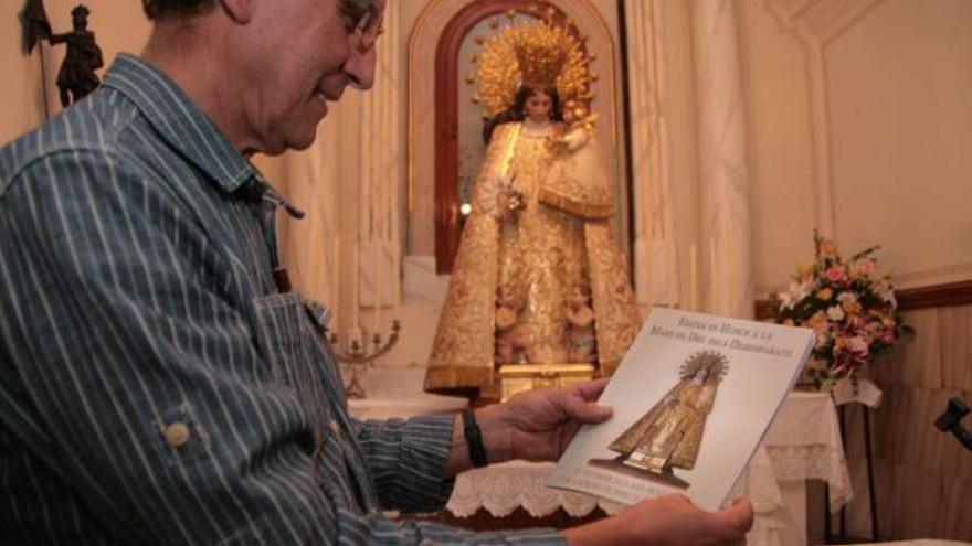 Manuel Reig muestra la revista del aniversario con la imagen de la Mare de Déu al fondo.