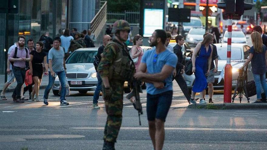 Viandantes junto a un soldado armado en el exterior de la Estación Central de trenes de Bruselas. // Efe