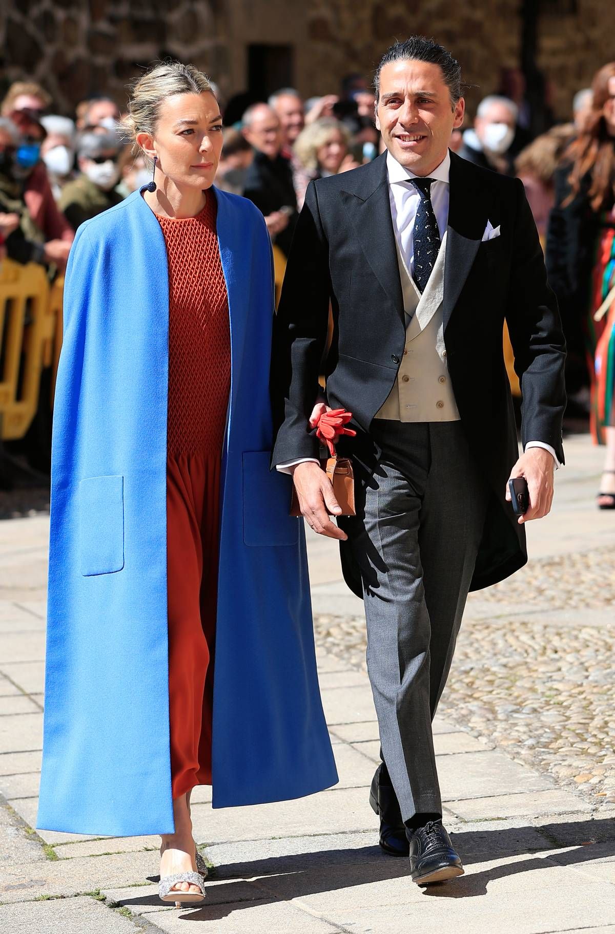 Marta Ortega con capa azul sobre un vestido color azafrán junto a Carlos Torreta