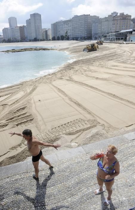 Las máquinas extienden la arena en la playa de Riazor.