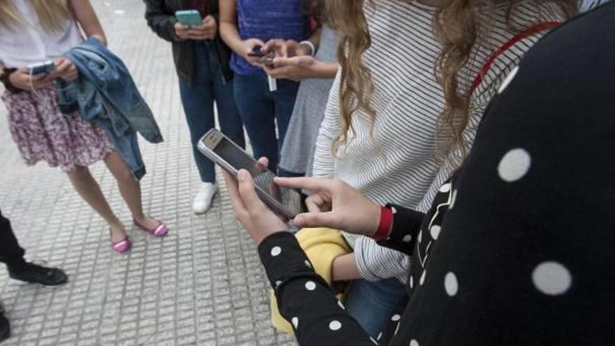 Varias adolescentes consultan sus teléfonos a la salida del instituto.