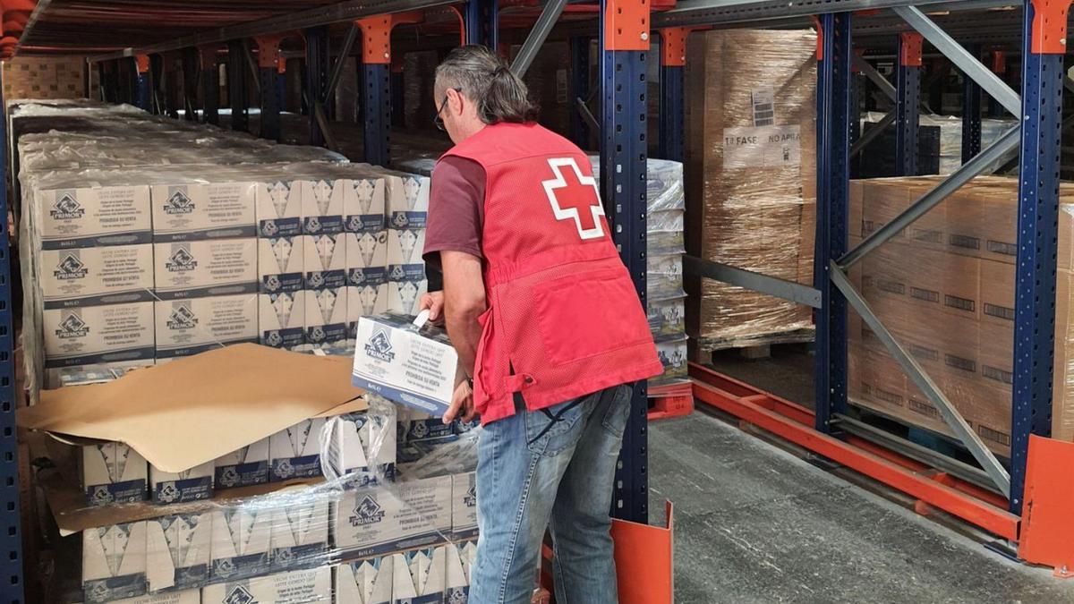 Un voluntario de Cruz Roja prepara cajas de alimentos para repartir a la población.