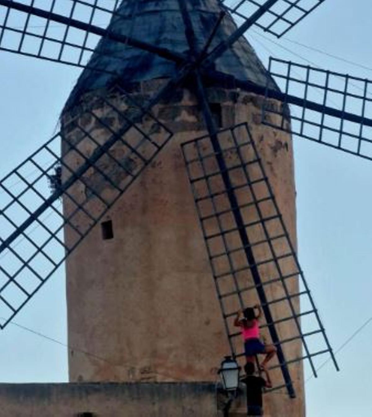 Dos personas se agarran a las astas del molino para intentar subir más arriba.