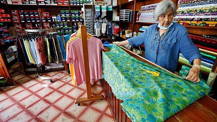 Dorita mide una tela con un metro antiguo en la tienda.