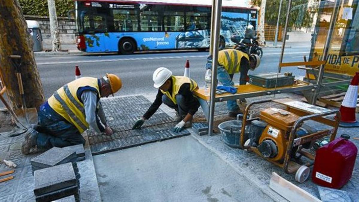 Instalación de las nuevas baldosas diferenciadas en una parada de bus situada en el paseo de la Bonanova, poco antes de llegar a Anglí, ayer.