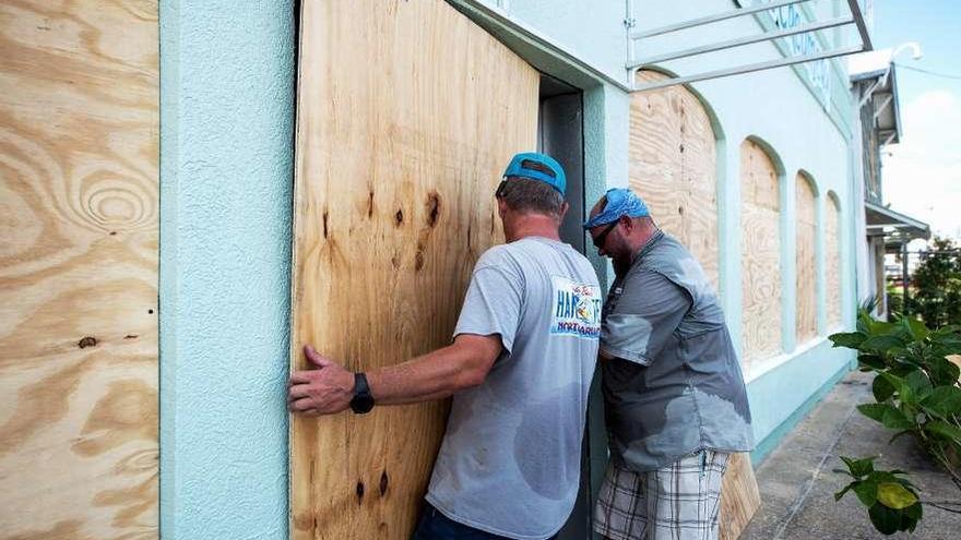 Dos personas apuntalan puertas y ventanas ante la llegada del huracán.  // EFE