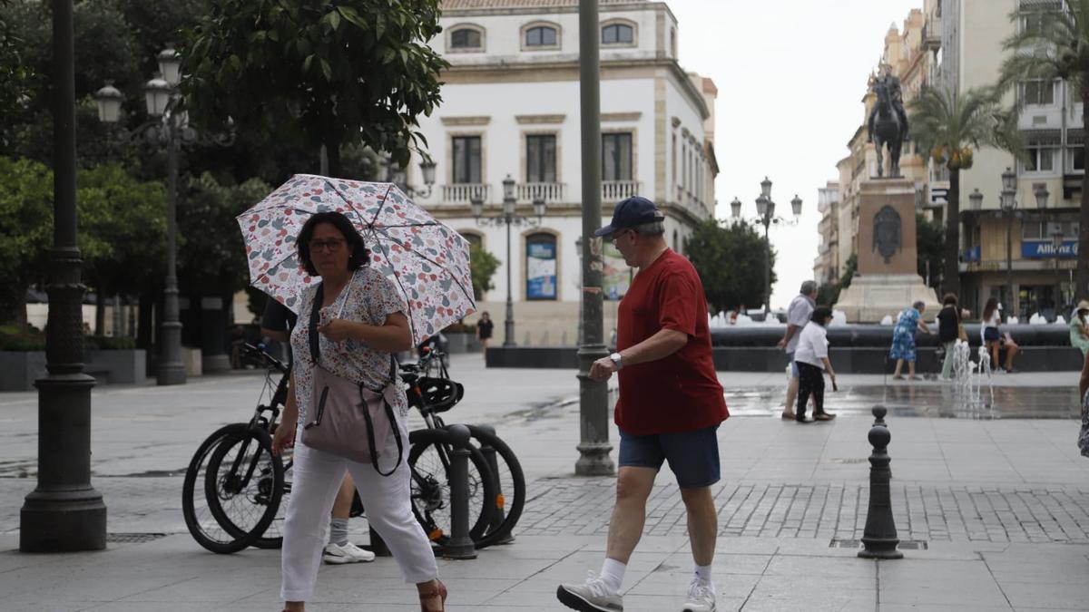Una mujer se cubre con un paraguas mientras llueve en Las Tendillas, esta mañana de sábado.
