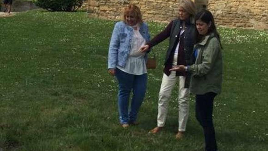 Cristina Coto, en el centro, señalando un charco junto a la iglesia de Santullano.