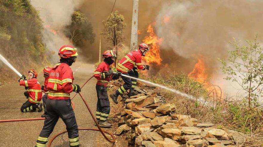 Varios bomberos intentan controlar el fuego en la localidad lusa de Sandinha.