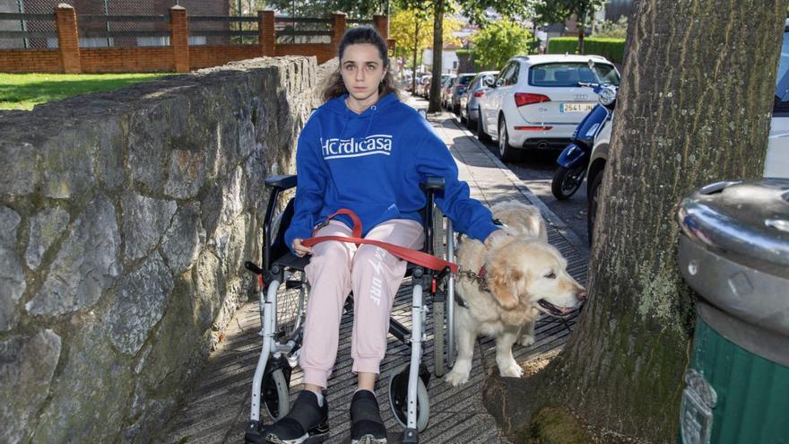 Carmen López, con su perra «Luna», en una acera de Ciudad Naranco limitada por un árbol y una papelera. | D. Cabo