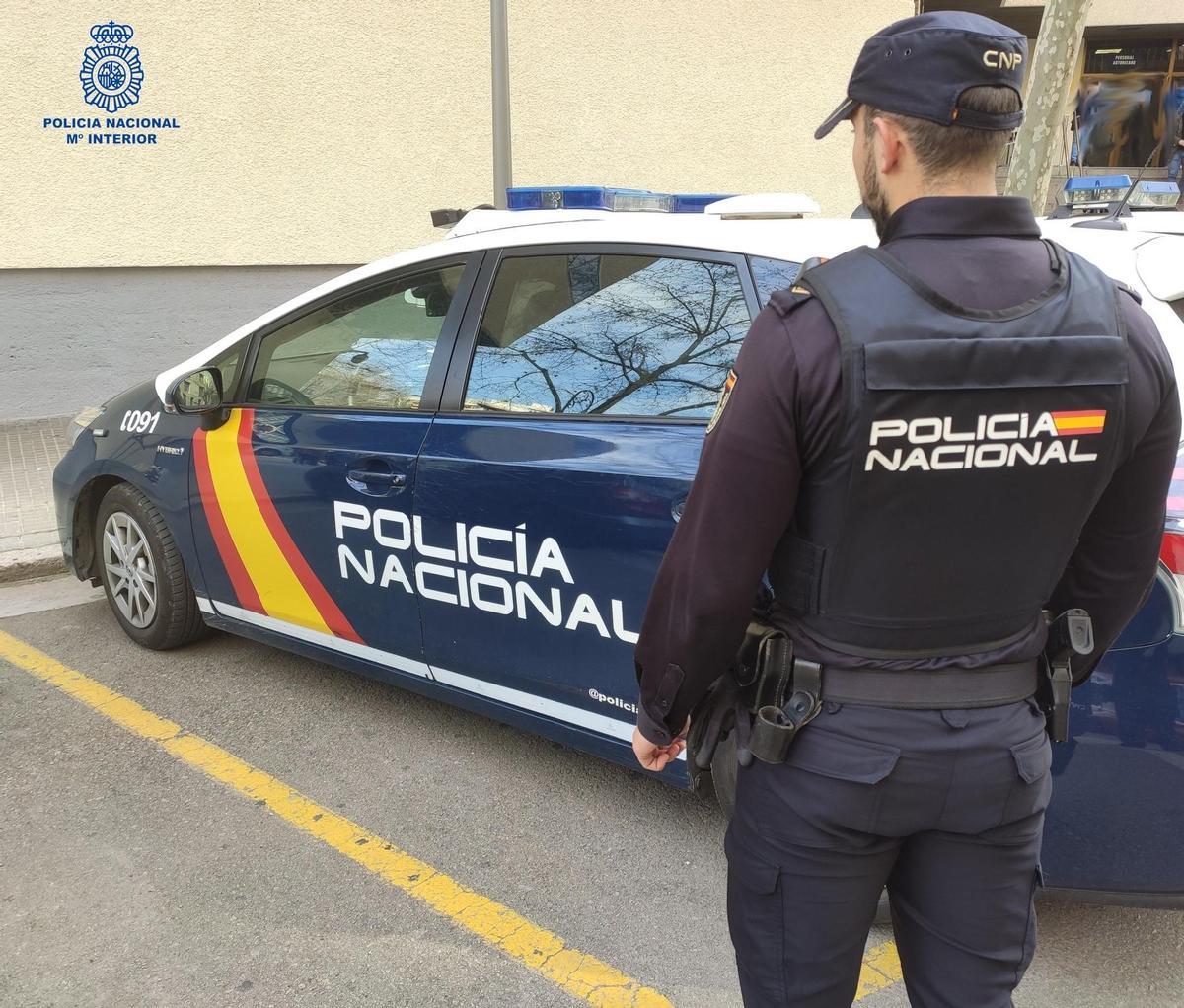 Un agente de la Policía Nacional junto al coche policial.
