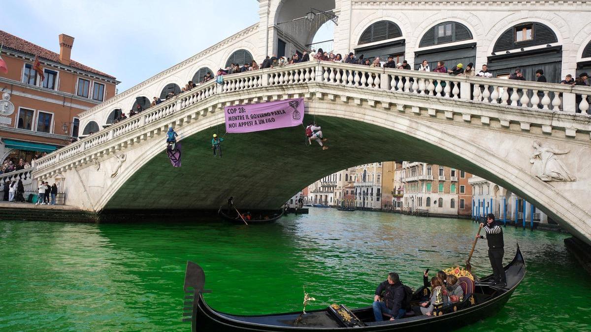 La gente viaja en barcos mientras las aguas del Gran Canal se vuelven verdes después de una protesta de activistas climáticos de la Rebelión de Extinción en Venecia.