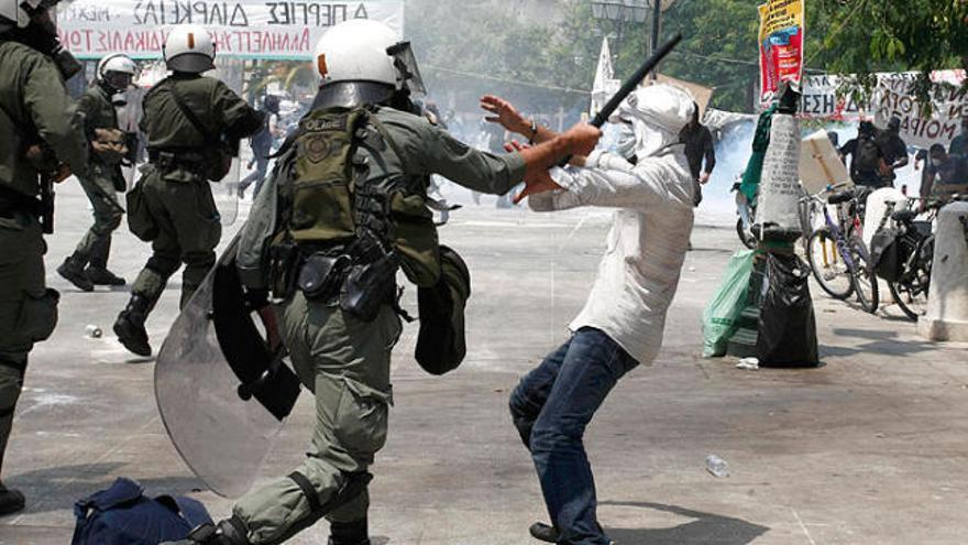 Un policia carrega contra un manifestant a Atenes.