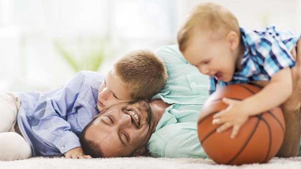 Un padre juega con sus hijos.