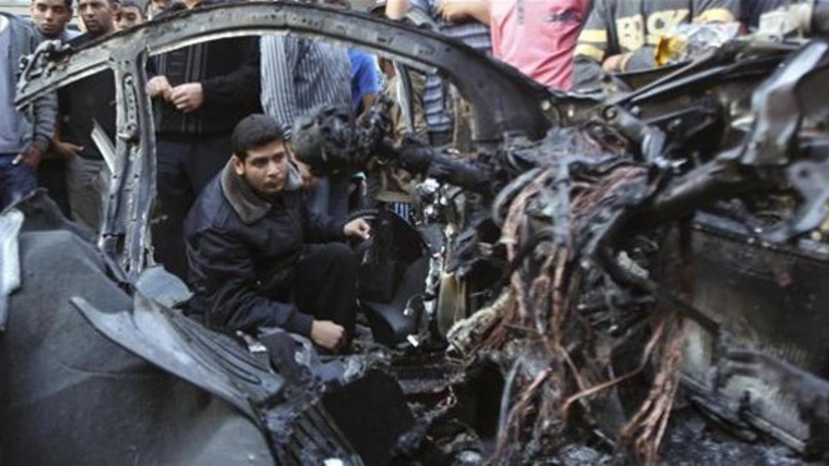 Un policía de Hamás inspecciona el coche destruido del jefe de la organización palestina tras el ataque israelí, este miércoles en Gaza.