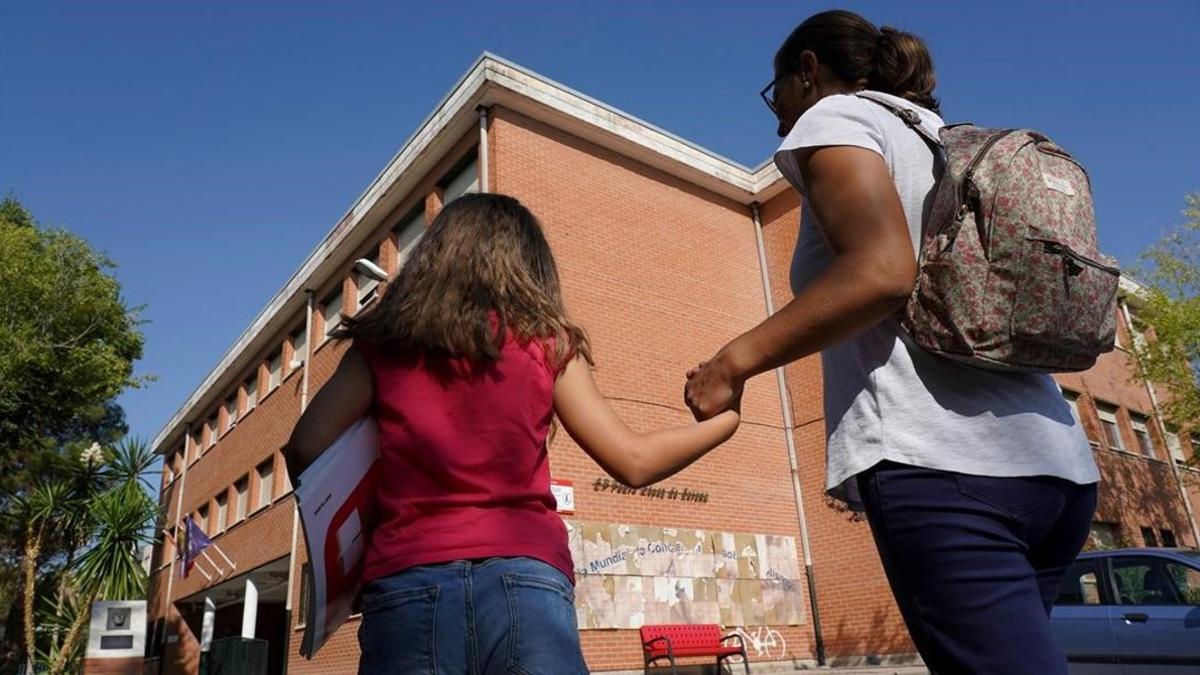 Una madre acompaña a su hija al colegio para recoger los libros de texto, el pasado martes en Madrid