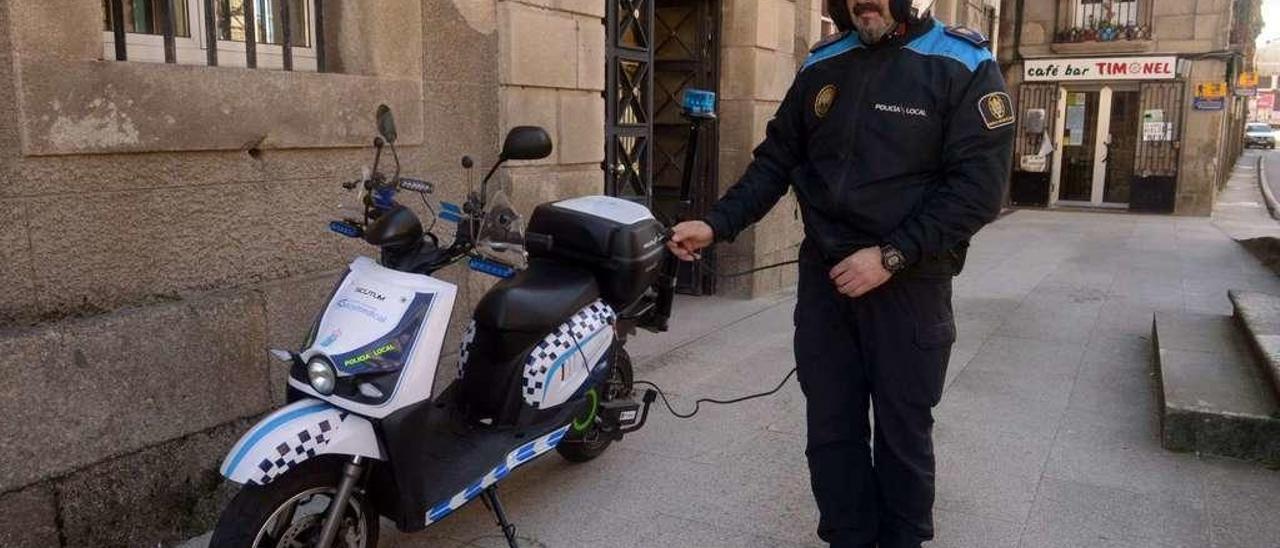 Un agente de Policía sujeta el cable de carga de la moto eléctruca. // Noé Parga