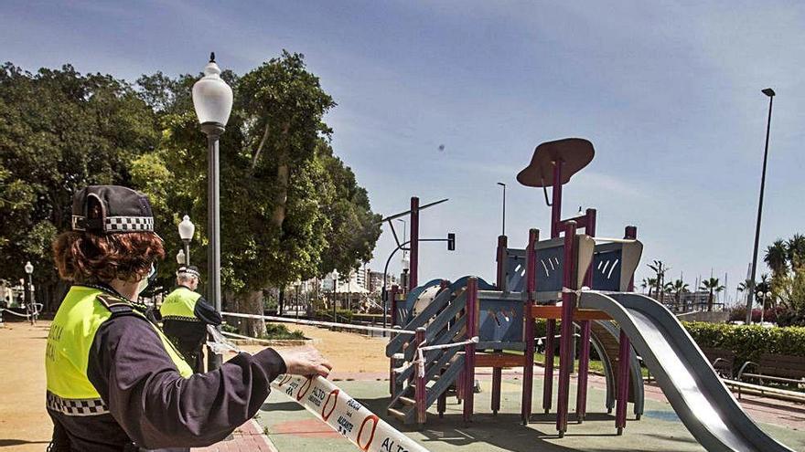 Una policía local renueva el precinto de un parque infantil de Alicante.