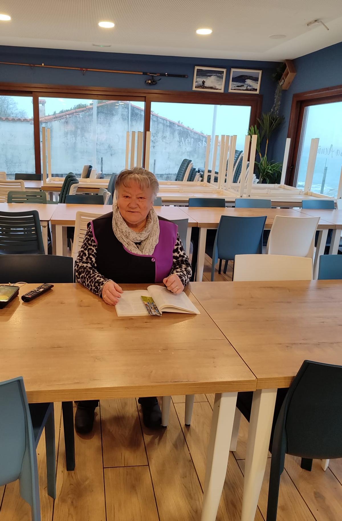 Una de las vecinas que está estos días en Ons, Palmira Acuña, ayer por la tarde en el bar de su familia aprovechando las horas de luz para leer.