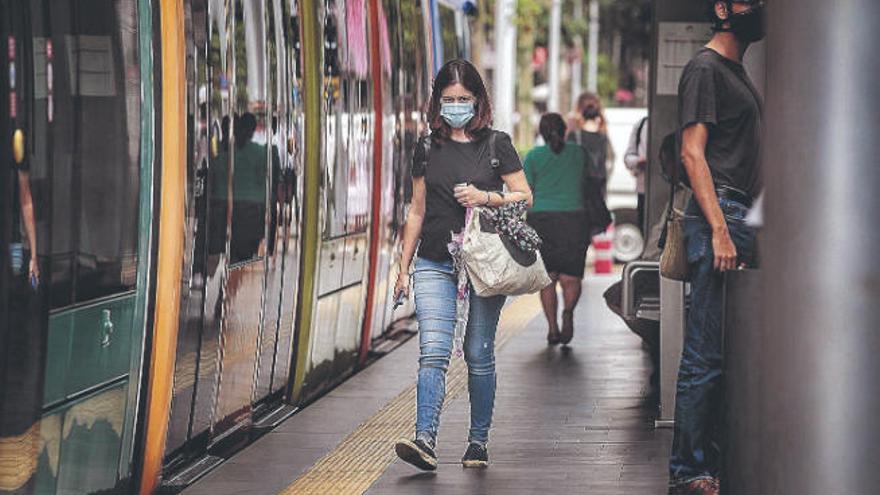 Una joven con mascarilla pasa junto al tranvía en Santa Cruz de Tenerife.