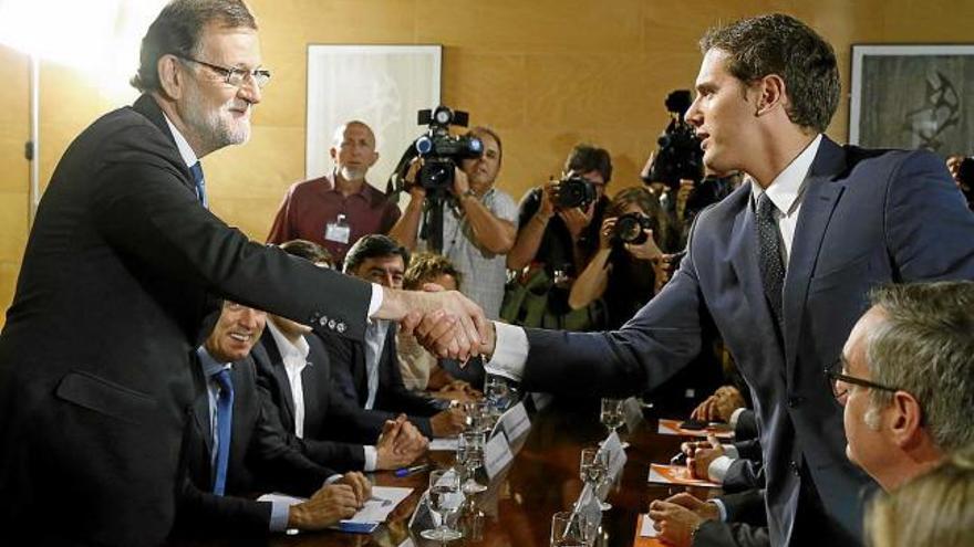 Mariano Rajoy i Albert Rivera es donen la mà després de formalitzar la signatura del pacte d&#039;investidura