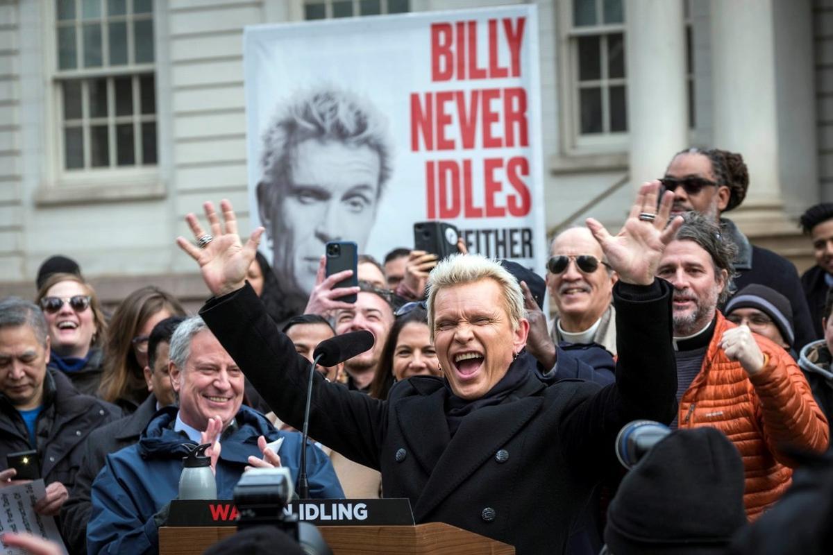 AME8772. NUEVA YORK (ESTADOS UNIDOS), 27/02/2020.- Fotografía cedida por el Ayuntamiento de Nueva York donde aparece la estrella del rock Billy Idol (d) mientras celebra junto al alcalde de la ciudad, Bill de Blasio (i-atrás), durante la presentación de una campaña medioambiental este jueves, en Nueva York (EE.UU.). Billy Idol participó este jueves en la presentación de una campaña medioambiental en Nueva York que pretende reducir el número de vehículos que, pese a no estar en marcha, permanecen con el motor encendido y por lo tanto contaminan de manera innecesaria. La iniciativa, titulada Billy nunca está inactivo, y tú tampoco deberías (Billy Never Idles, Neither Should You), está impulsada por el Ayuntamiento de Nueva York, y pide a los neoyorquinos que informen de los conductores que no apagan el motor cuando están detenidos. EFE/ Michael Appleton/ Ayuntamiento de Nueva York SOLO USO EDITORIAL/NO VENTAS