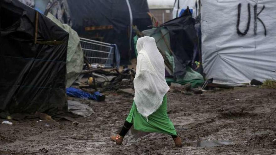 Una inmigrante eritrea camina por el barro en los campamentos de Calais. // Reuters