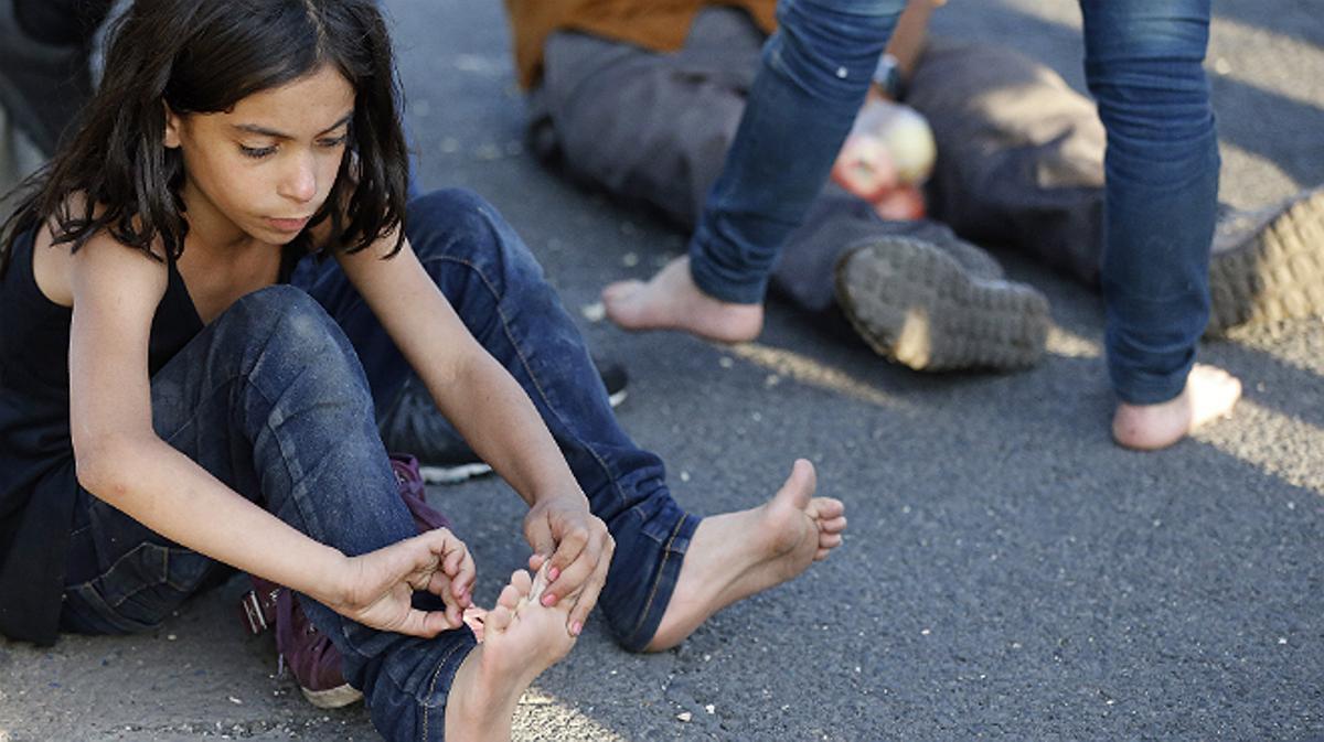 Una niña se cuida los piés durante la marcha de refugiados de Budapest hacia Alemania. 