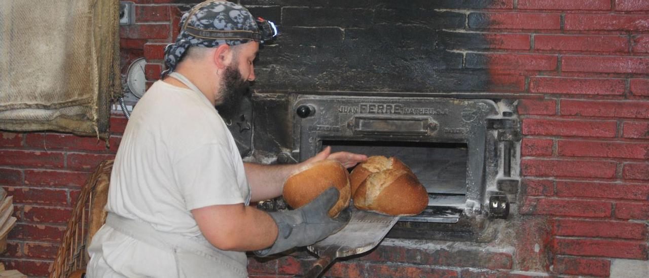 Un forner traient el pa cuit al forn de llenya que Eixarcolant té a Jorba | JORDI BADIA PEREA