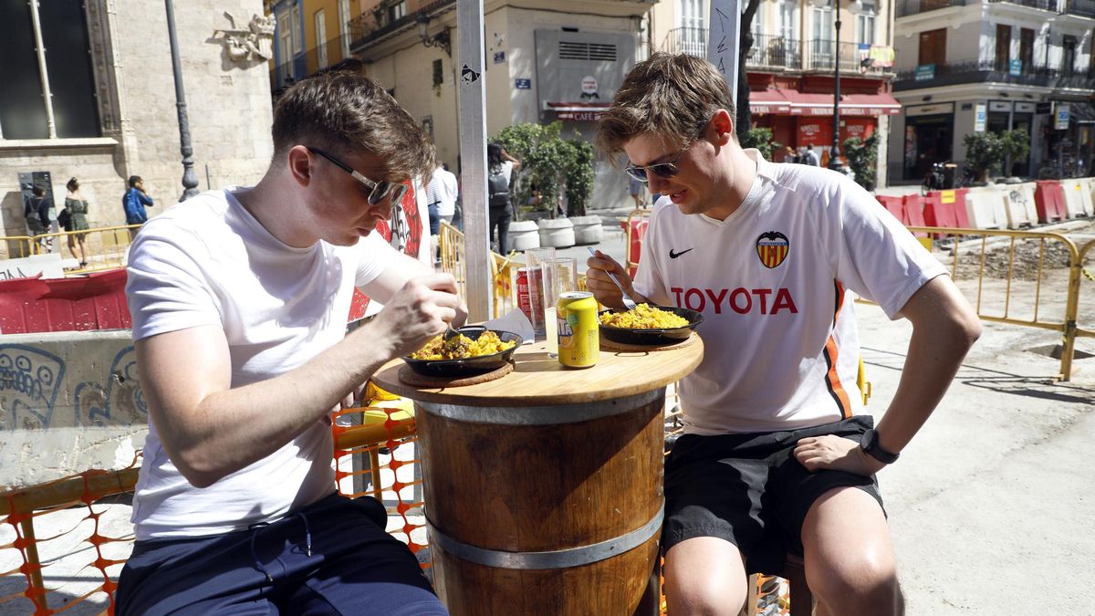 Dos turistas comiendo paella en la plaça del Mercat de València.