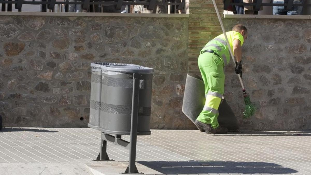 Un barrendero limpia una acera de la calle de Mallorca.