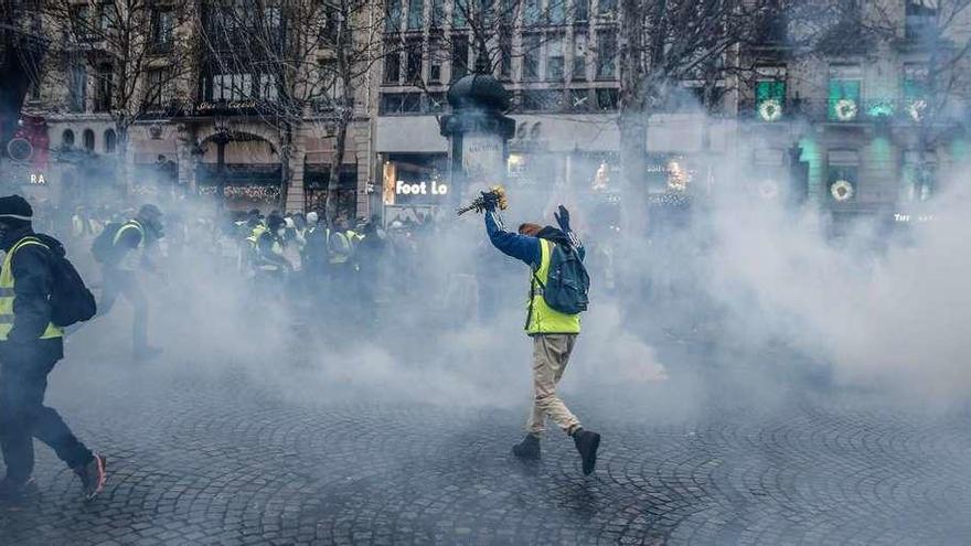 Participantes en la protesta, en medio de los gases arrojados por la Policía, ayer en París. // AFP
